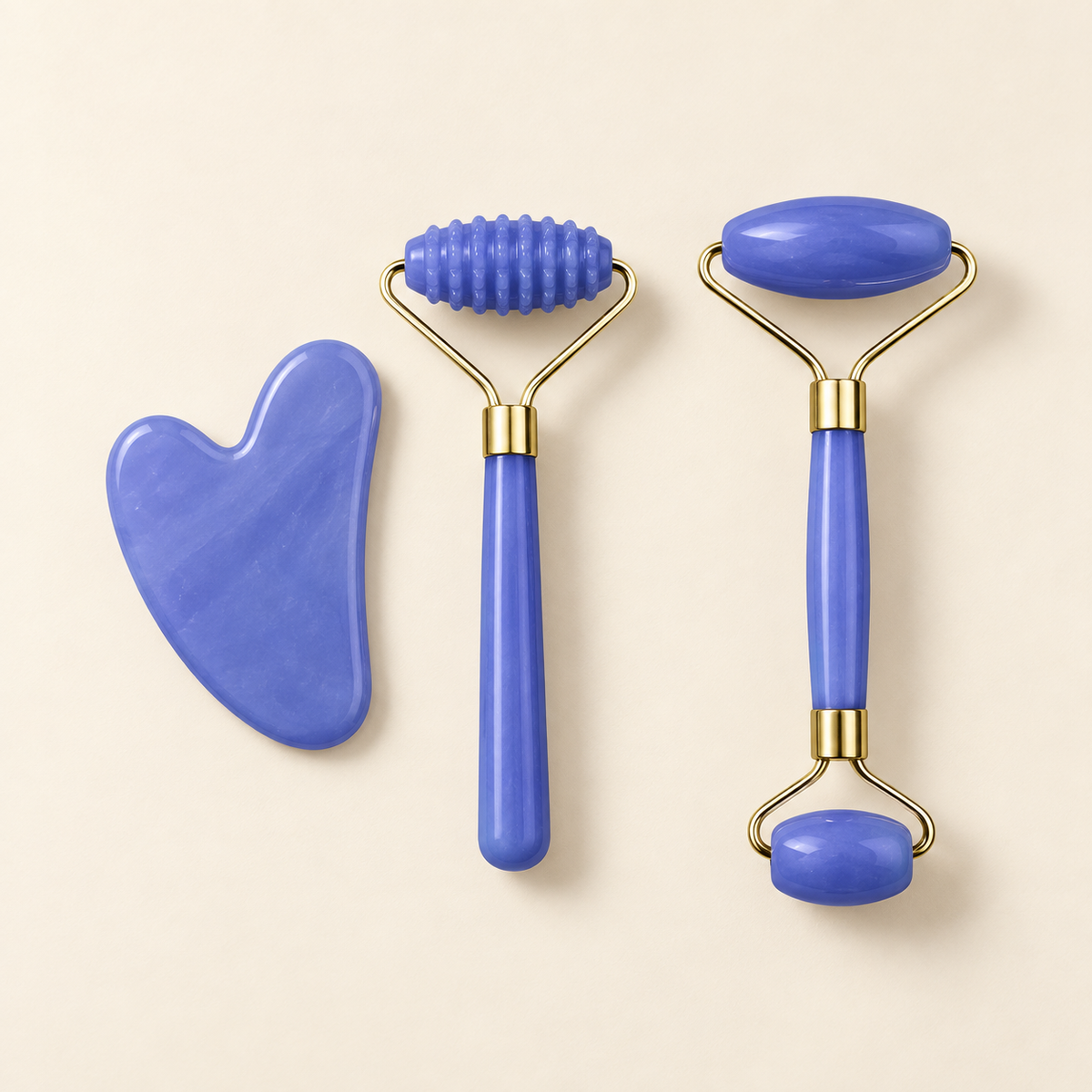 Set de rodillos faciales y gua sha azul sobre fondo crema